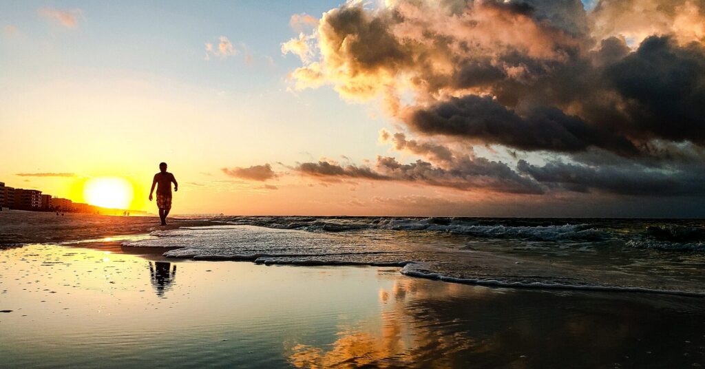Person walking along the shoreline at sunset